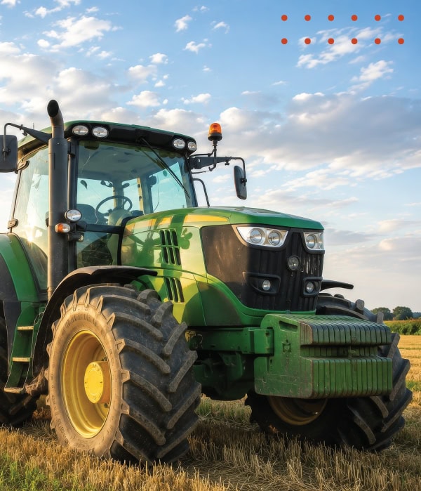 Green agricultural tractor in a field representing the equipment manufacturing industry